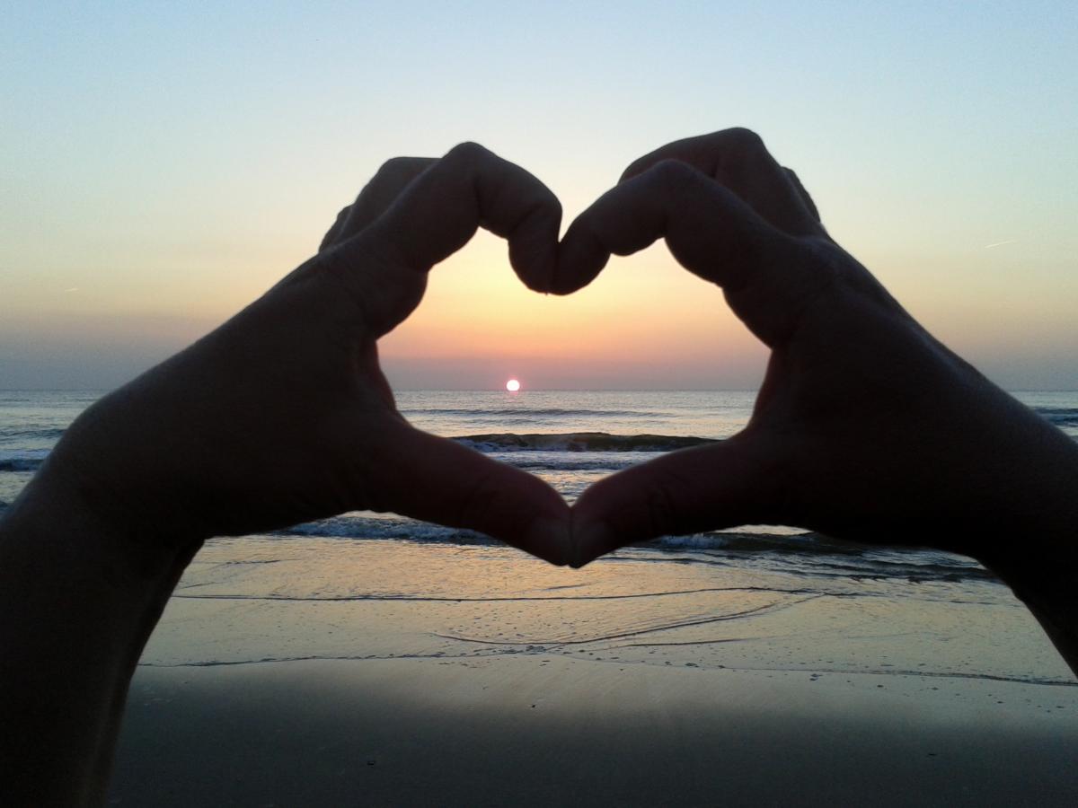 Händeherz vor einem Sonnenuntergang